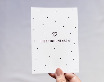 May include: White card with black polka dots and the text "LIEBLINGS MENSCH" with a small heart above the text.