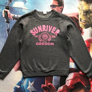 May include: Gray sweatshirt with a pink graphic print of the text "Sunriver Est. 1968 Oregon" with a sun and wreath design.