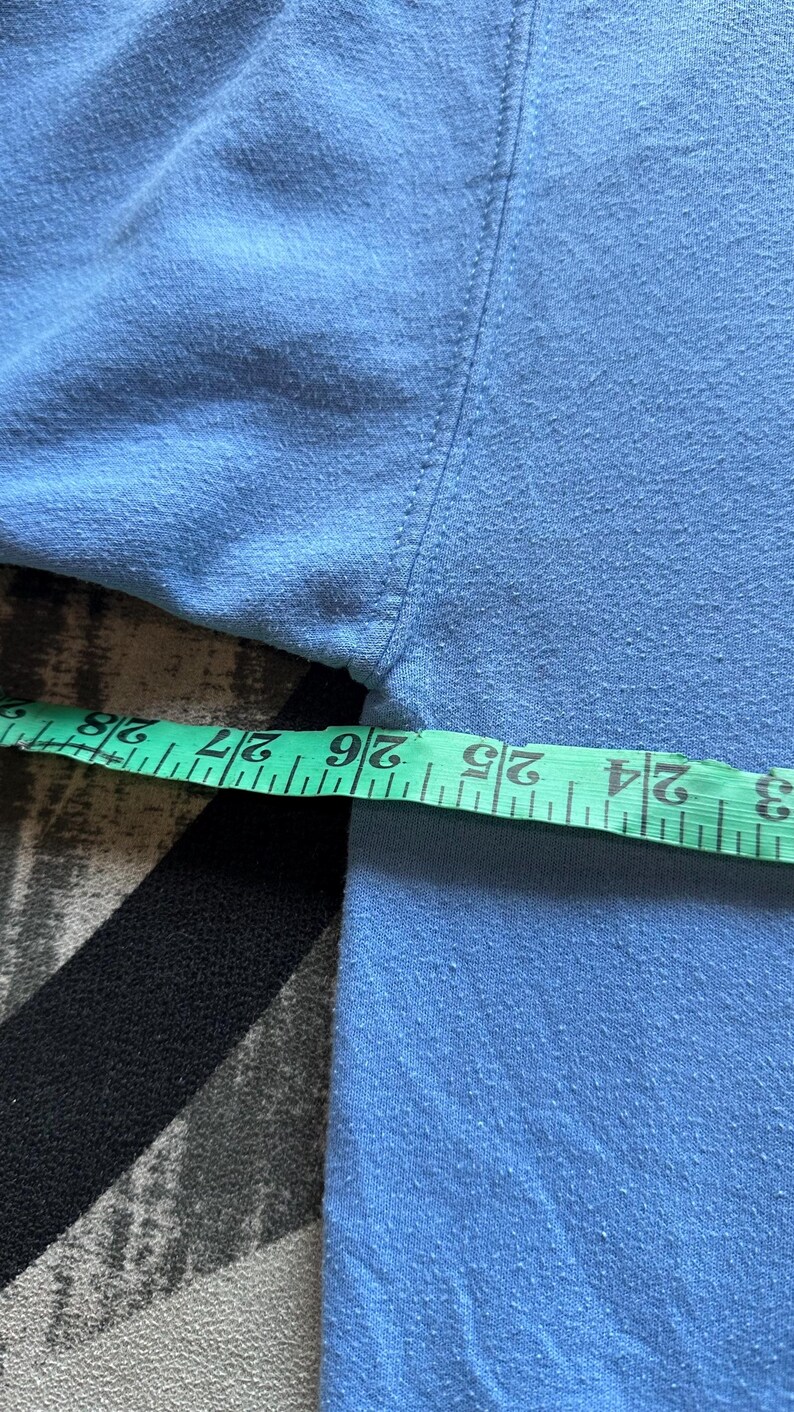 Peut inclure: Un gros plan sur un tissu bleu clair avec un ruban &agrave; mesurer indiquant 26 pouces.