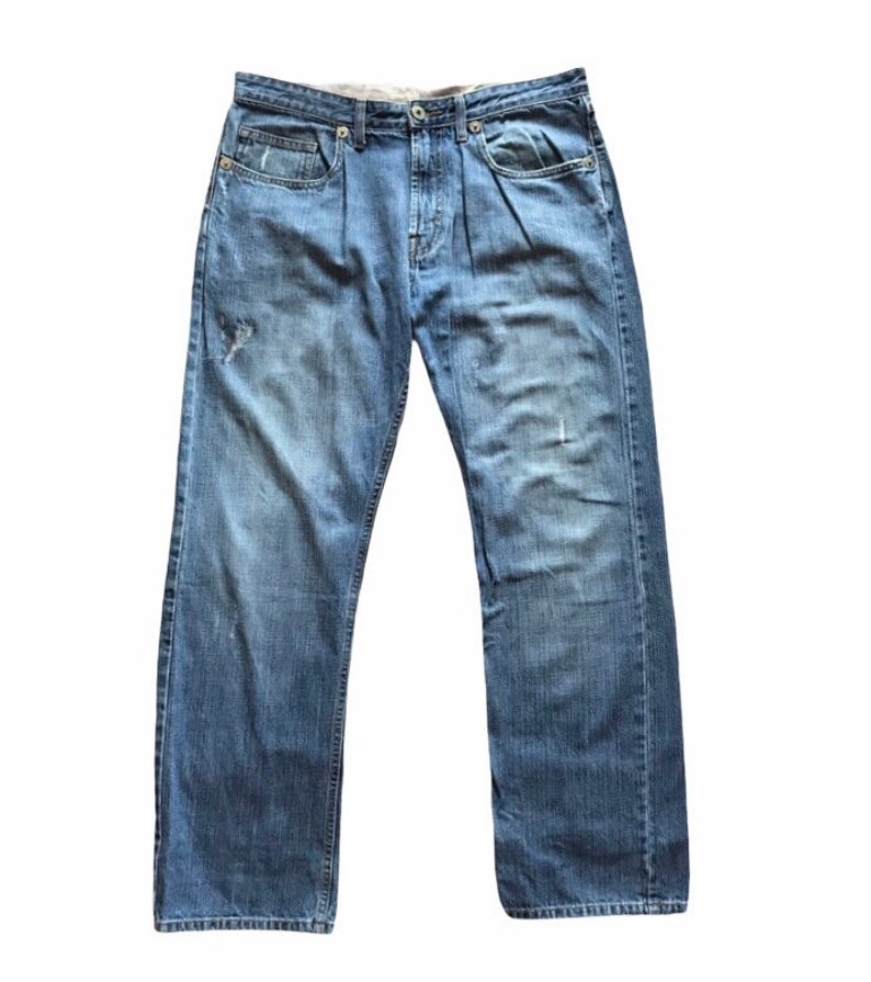Peut inclure: Jean en denim bleu d&eacute;lav&eacute; avec une conception classique &agrave; cinq poches. Le jean a une coupe droite et un aspect us&eacute; avec quelques petites d&eacute;chirures. Le jean est &agrave; braguette boutonn&eacute;e et a un lavage clair.