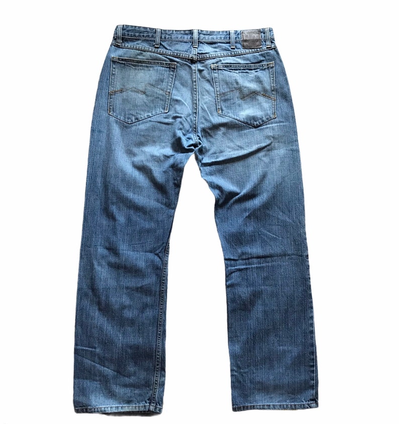 Peut inclure: Jean bleu clair avec une coupe droite classique &agrave; cinq poches. Le jean pr&eacute;sente un aspect d&eacute;lav&eacute; avec des marques d'usure visibles. Les poches arri&egrave;re ont des coutures d&eacute;coratives subtiles. Fabriqu&eacute; en denim durable.