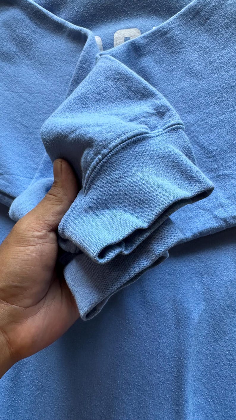 Peut inclure: Un gros plan sur le poignet pli&eacute; d'un sweat-shirt bleu clair. Le tissu est doux et textur&eacute;.