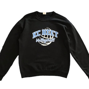 May include: Black sweatshirt with the text "KC HEET Volleyball" in light blue and white. The text is centered on the front of the sweatshirt, above a white volleyball graphic.