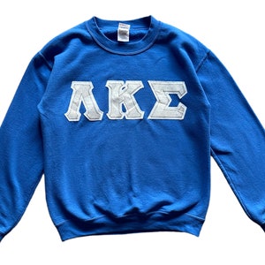 Peut inclure: Un sweat-shirt bleu avec des lettres blanches qui lisent "AKE".