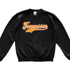 May include: Black sweatshirt with a large orange and white "Tennessee" graphic in a vintage baseball font.