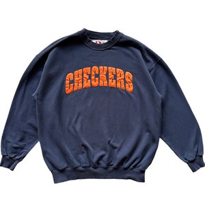 Può includere: Una felpa blu navy con la parola "CHECKERS" ricamata in arancione sul davanti.