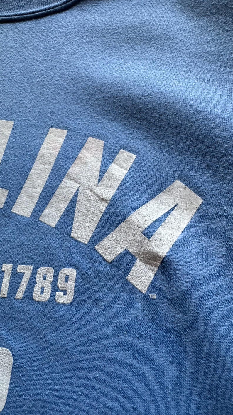Peut inclure: Un t-shirt bleu avec un lettrage blanc qui dit "INA 1789" avec un symbole de marque d&eacute;pos&eacute;e.