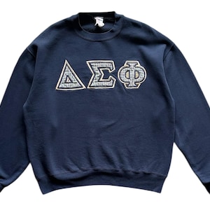 Peut inclure: Un sweat-shirt bleu marine avec un motif brodé de lettres grecques blanches et beiges qui lit "ΔΣΦ".