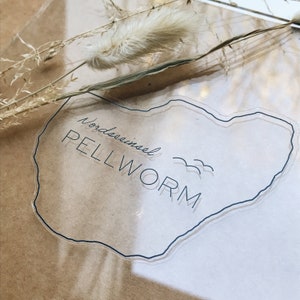 Könnte beinhalten: Ein transparenter Aufkleber mit braunem Umriss in Form einer Insel. Der Aufkleber zeigt den Text "Nordseeinsel Pellworm" mit einem stilisierten Bild von drei Möwen.