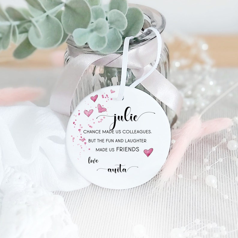Puede incluir: Adorno de cer&aacute;mica blanca con corazones de acuarela rosa y el texto "julie CHANCE MADE US COLLEAGUES. BUT THE FUN AND LAUGHTER MADE US FRIENDS love anita"