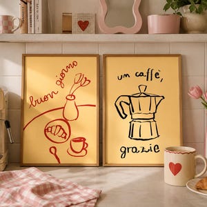 May include: Two framed art prints with yellow backgrounds. One features a red illustration of a croissant, coffee cup, and vase with tulips, with the words "buon giorno." The other shows a coffee maker illustration with the words "un caffè, grazie."