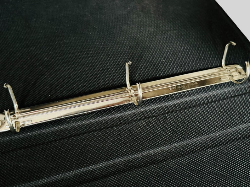 May include: A silver binder mechanism with three rings and the text "WORLD WIDE" engraved on the metal.