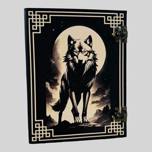 May include: Black leather journal with a wolf silhouette design against a full moon. The cover features a decorative gold frame with intricate patterns.