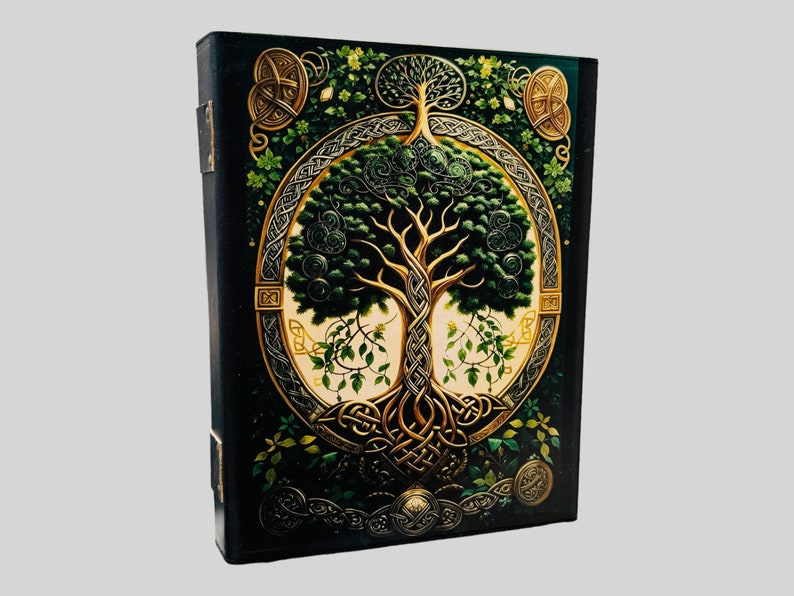 May include: A black leather journal with a gold Celtic knot design featuring a green tree of life. The journal has a decorative spine and a gold clasp.