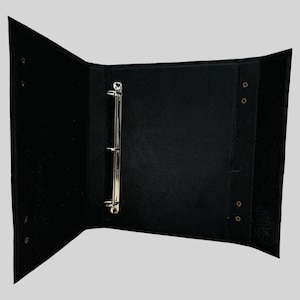 May include: Black three-ring binder with metal rings and brass grommets.