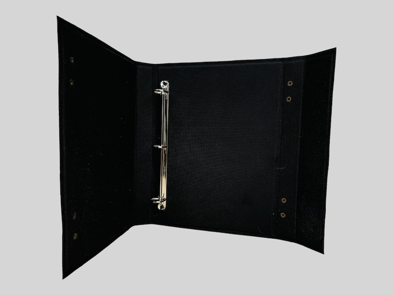 May include: Black three-ring binder with metal rings and brass grommets.