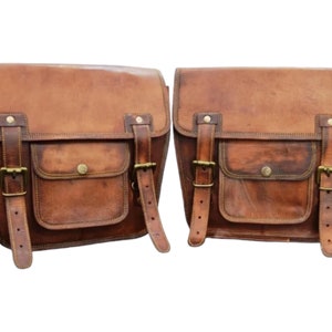 May include: A pair of brown leather motorcycle saddlebags with buckles and a front pocket.