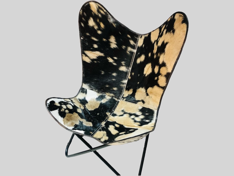 Op de afbeelding: Een zwart-witte butterfly stoel van koeienhuid met een zwart metalen frame.