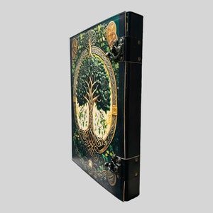 May include: A dark green leather-bound journal with a Celtic tree of life design. The cover features intricate gold details and a tree with green leaves. The journal has two metal clasps.