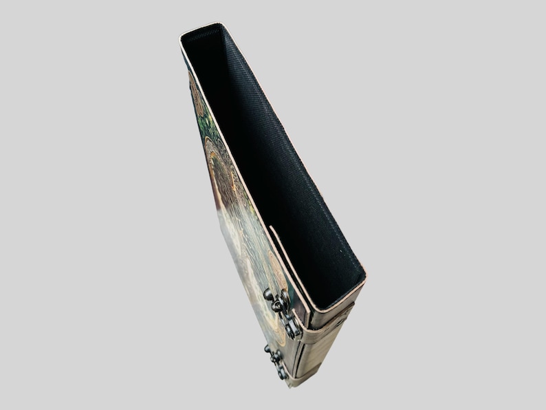 May include: A brown leather journal with a colorful, intricate design on the front cover. The journal has a black fabric lining and metal accents.
