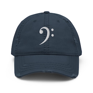 Peut inclure: Casquette de baseball bleu marine vieillie, ornée d'une broderie blanche représentant une clé de sol. La casquette a une visière incurvée et un aspect usé. Un accessoire de mode pour les mélomanes.