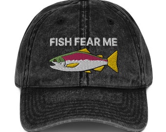 Peut inclure: Une casquette de baseball en coton vintage noir délavé avec un saumon brodé et le texte "FISH FEAR ME".