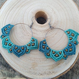 Könnte beinhalten: Ein Paar türkisfarbene und braune Makramee-Hoop-Ohrringe mit Perlenmuster.