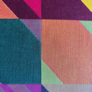 May include: Abstract textile pattern featuring geometric shapes in vibrant colors. The design includes squares and diagonal lines in shades of pink, purple, teal, orange, and yellow. The fabric has a textured appearance.