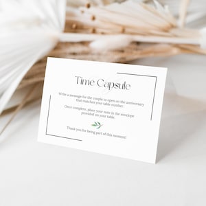 May include: A white card with the words "Time Capsule" in elegant script. The card includes instructions for writing a message for a couple to open on their anniversary, with a small green leaf illustration.