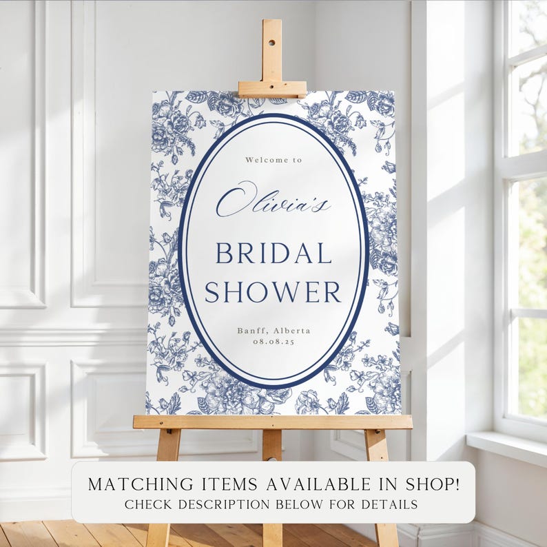 May include: A white sign with blue floral patterns and text that reads "Welcome to Olivia's Bridal Shower" with the date and location. The sign is displayed on a wooden easel. The text "Matching items available in shop! Check description below for details" is at the bottom.
