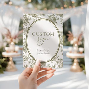 Könnte beinhalten: Rechteckiges individuelles Schild mit floralem Design und den Worten "CUSTOM sign" in einem ovalen Rahmen. Das Schild enthält auch den Text "Design unlimited custom signs for your celebration!"