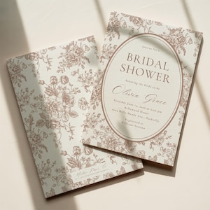 Puede incluir: Dos tarjetas de papel rectangulares con fondo crema claro y un patrón floral marrón. La tarjeta de la derecha muestra un marco ovalado con el texto: Join us for a BRIDAL SHOWER honoring the bride-to-be Olivia Grace, Saturday June 14, 2026 at 6:00 pm, Bellewood House, 1604 Belle Meade Ave., Nashville, Registered at Williams Sonoma.