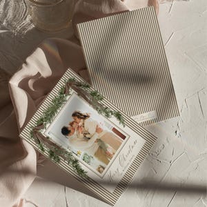 Editable neutral Christmas photo card template with family photos, classic stripe details, and festive greenery, perfect for a sophisticated personalized holiday greeting