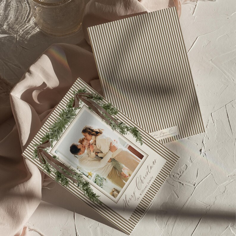 Editable neutral Christmas photo card template with family photos, classic stripe details, and festive greenery, perfect for a sophisticated personalized holiday greeting