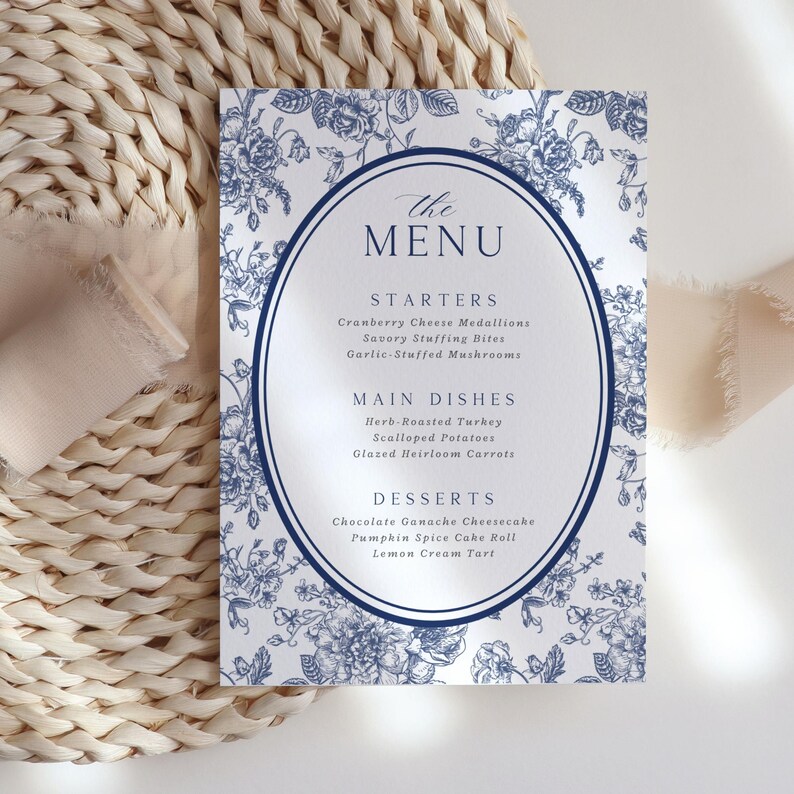 May include: A printed menu card with a floral design in blue and white. The menu is titled "The MENU" and lists starters, main dishes, and desserts. The card is placed on a woven surface.