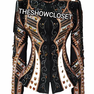 Puede incluir: Chaqueta de exhibición negra con intrincados adornos. Presenta un cuello alto y una cremallera central. La chaqueta está adornada con cristales de cobre, oro y transparentes, y detalles blancos. El texto "THESHOWCLOSET" está en el pecho.