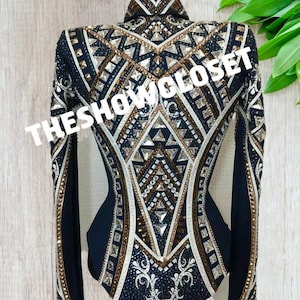 May include: A black show shirt with a geometric design featuring gold, white, and silver accents. The shirt has long sleeves and a fitted silhouette.