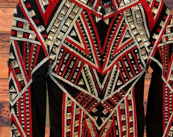 May include: A black show jacket with a striking design featuring red and silver geometric patterns. The jacket has a black collar and sleeves, adorned with rhinestones and metallic details. The design incorporates a central V-shape and vertical lines, creating a bold look.
