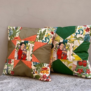 May include: Two decorative throw pillows with a patchwork design. One pillow is green with a yellow and white floral pattern and the other is orange with a green and white floral pattern. Both pillows feature a portrait of a woman with a monkey.