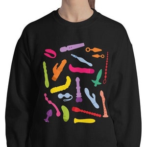 May include: A black sweatshirt with a colorful pattern of various shapes and designs. The pattern is made up of different colors, including pink, blue, green, yellow, and orange.