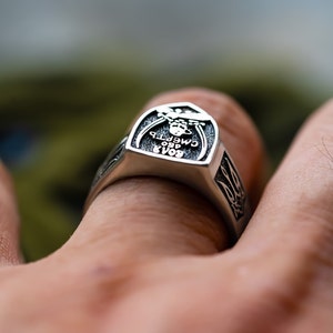 May include: A silver ring with a raised design featuring a skull and the text "БОЯР 1980 СМЕРТЬ". The ring is worn on a person's finger.