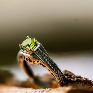 May include: A silver ring with an ornate design and a green gemstone.