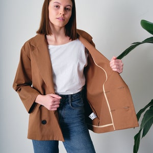This oversized cotton jacket offers both comfort and freedom of movement. Crafted from 100% organic cotton with GOTS certification. Suitable for various occasions, this loose-fitting blazer complements both casual and formal looks.