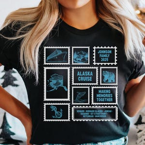 以下が含まれることがあります： アラスカクルーズ、船、クマ、その他のアラスカのイメージの青い切手のようなデザインが特徴の黒いTシャツ。「アラスカクルーズ」、「Making Memories Together」、「Johnson Family 2025」の文字が含まれています。