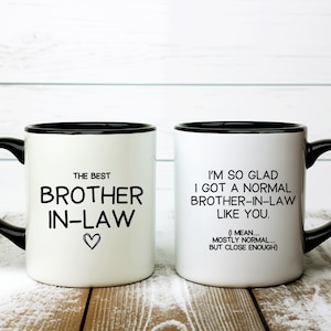 May include: Two white ceramic mugs with black handles and rims. One mug reads "THE BEST BROTHER IN-LAW" with a heart. The other mug says "I'M SO GLAD I GOT A NORMAL BROTHER-IN-LAW LIKE YOU."