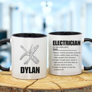 May include: White ceramic mug with a black handle and rim. The mug features the name "DYLAN" in bold black letters, along with illustrations of a screwdriver and pliers. The other side of the mug has the word "ELECTRICIAN" and a definition.