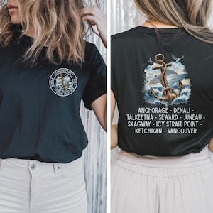 以下が含まれることがあります： 「Johnson Family Cruisin Together」の文字が入った円形デザインの黒いTシャツ。背面には、錨とアラスカの地名が描かれたクルーズ船のグラフィックが表示されています。