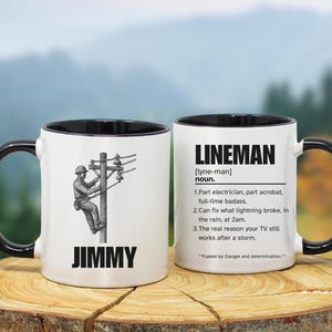 May include: White ceramic mug with a black handle and rim. One side features a lineman climbing a utility pole with the name "JIMMY" below. The other side has the definition of "LINEMAN" with humorous descriptions.