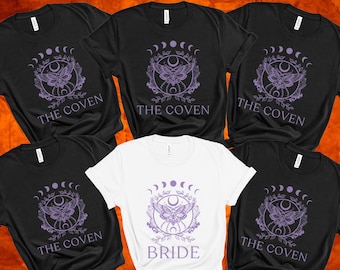 May include: Six black t-shirts with a purple moth and crescent moon design and the text "The Coven" printed on them. One white t-shirt with the same design and the text "Bride" printed on it.