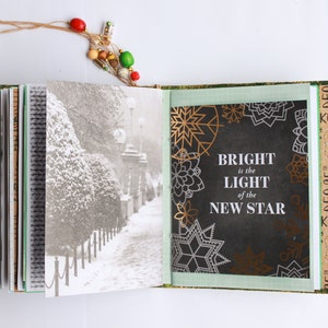 May include: An open book with a black and white photo of a snowy path on the left page and a black background with gold and white snowflakes and the text "BRIGHT is the LIGHT of the NEW STAR" on the right page.